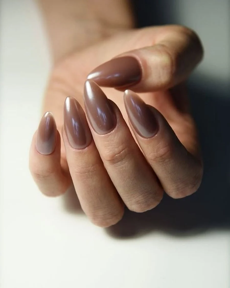 Warm brown almond nails worn on a hand